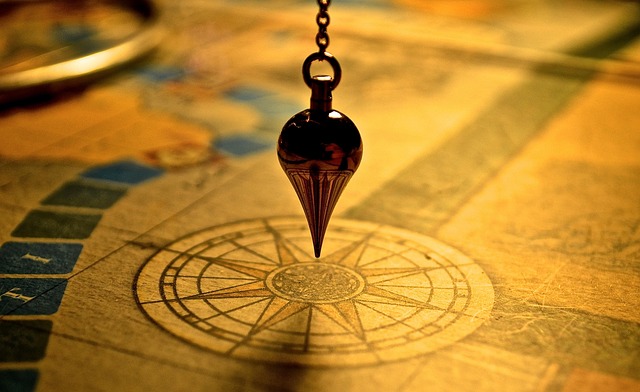 A pendulum hovering over a compass on a map